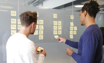 two men discussing product lifecycle with post-its on board